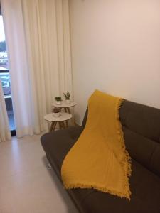a living room with a couch with a yellow blanket at RUA PLANA, 2qts, 2 banh, VARANDA c CHURRASQUEIRA, estacionamento, ELEVADOR, portaria in São Lourenço