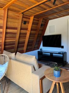 a living room with a couch and a flat screen tv at Chale Blue Lodge in São Pedro