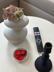 a white vase with flowers in it next to a remote control at Lovely 1BR & 1LR Apartment, Only 15 Min Walk to City Center in Ghent