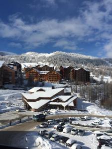 un aparcamiento cubierto de nieve con edificios y coches en beau duplex marmotiere, en Risoul