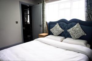 a bedroom with a large white bed with a blue headboard at The Old Court House in Kingswinford +1 photo