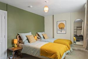 two beds in a room with green walls at Cottage in central Porlock with garden & parking in Porlock