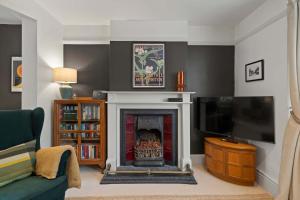 a living room with a fireplace and a tv at Cottage in central Porlock with garden & parking in Porlock