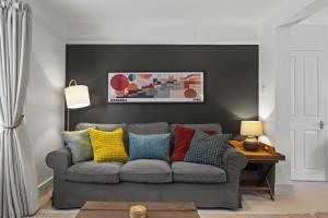 a living room with a gray couch with colorful pillows at Cottage in central Porlock with garden & parking in Porlock