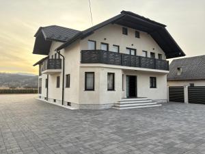 a large white house with a balcony on a driveway at Casa Pop in Petrova