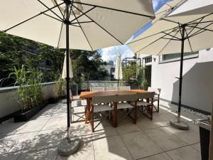 un patio con una mesa de madera y 2 sombrillas en Green Residence Boutique Lofts & Villa am Park, en Offenbach 188 fotos más
