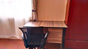 a desk with a chair next to a window at Deluxe Homes, Voi in Voi