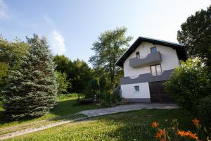 a white house with a garage in a yard at Holiday Home Tin in Ogulin