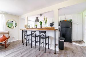 a kitchen with a bar with stools and a refrigerator at Short North - Convention - Private Parking - Pets - 2BR in Columbus