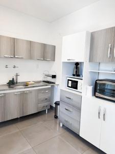 eine Küche mit weißen und grauen Schränken und Geräten in der Unterkunft Dpto ubicacion perfecta cuatro habitaciones tres baños en calle caseros, renovado y remodelado - Bonavista Rentals in Salta