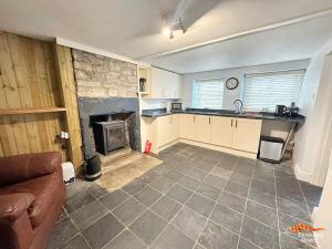 a kitchen with a living room with a fireplace at Hundy Cottage in Alston +10 photos
