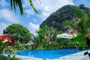 a resort swimming pool with a mountain in the background at Tam Coc Kamili Bungalow & Homestay in Ninh Binh