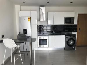 cocina con armarios blancos, mesa y lavavajillas en Amal Suites, en Accra