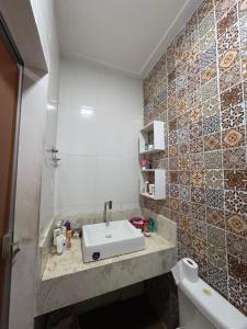 a bathroom with a sink and tiled wall at Casa completa para cop 30 in Belém