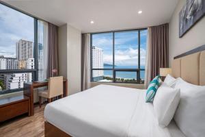 a bedroom with a bed and a desk and a large window at Avatar Danang Hotel in Da Nang