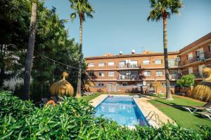 a hotel with a swimming pool in front of a building at Apartamentos Velor in Castelldefels