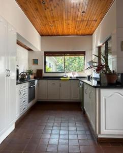a large kitchen with white cabinets and a wooden ceiling at Stone Trading Pty Ltd in Durban