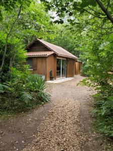 a cabin in the woods with a gravel road in front at Les Cabanes de Rouffignac in Rouffignac Saint-Cernin
