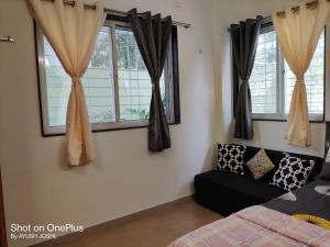 a bedroom with a couch and two windows at Pushpchhaya Home Stay in Nashik