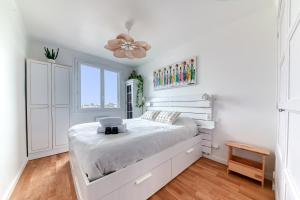 a white bedroom with a bed and a ceiling fan at Appartement Le perchoir - Welkeys in La Guillotière