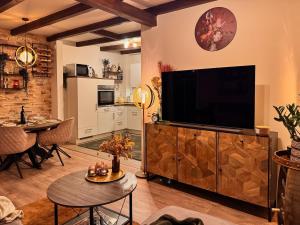 a living room with a large flat screen tv on a wooden entertainment center at Stall & Glut - Landhaus mit Sauna & Kaminofen in Bad Zwischenahn