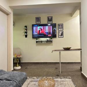 a living room with a flat screen tv on a wall at Cozy & Comfy 1BHK in Sector 46 in Noida +3 photos