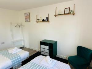 バーミンガムにあるModern & Cosy 2-Bed Apartment Near NEC, Airport & JLR!のベッド2台と緑の椅子が備わる客室です。