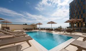 una piscina en la azotea de un edificio con sillas y sombrillas en Invictus Hotel, en Budva