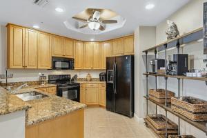 a kitchen with wooden cabinets and a black refrigerator at Fantastic Three Bedroom Condo With Balcony in Shell Point Village