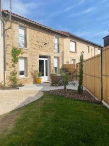 a house with a fence and a bench in a yard at L'Atelier Jolie maison de charme proche Puy duFou in La Flocellière