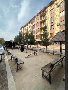 un parque con bancos y un parque infantil frente a un edificio en GoHostel, en Samarkand
