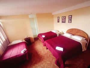 two beds in a hotel room with red sheets at Marlon's INN Cusco II in San Antonio