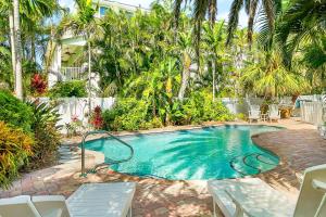a swimming pool in a yard with chairs and palm trees at Anna Cabana Bungalow #3 in Holmes Beach