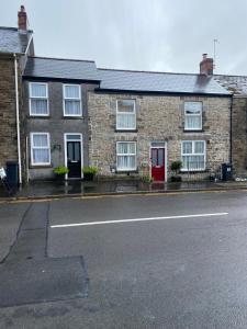a brick house with a red door on a street at Tŷ Twt in Pontardawe
