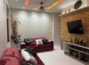 a living room with a red couch and a flat screen tv at Lar dos Fernandes in Belém