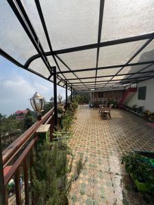 an outdoor patio with a roof with tables and benches at Samendu bhawan in Mirik