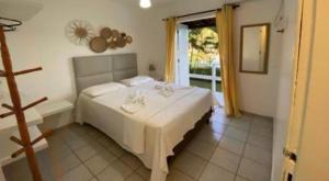 una camera da letto con un grande letto bianco e una finestra di Golden Dolphin Taperapuan Apt 529 a Porto Seguro Altre 27 foto