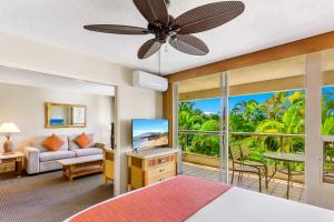a bedroom with a bed and a living room with a television at Maui Banyan Vacation Club in Wailea
