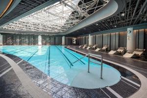 une grande piscine avec des chaises dans un bâtiment dans l'établissement Hangzhou Wulin GDA Hotel, Vignette Collection - Nearby the iconic Wulin Square, with only a few minutes' walk to the West Lake, à Hangzhou