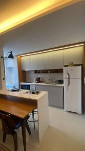 eine Küche mit einem Tisch und einem weißen Kühlschrank in der Unterkunft Ap Conforto 1002 - On São Mateus ar cond in Juiz de Fora