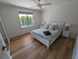 a white bedroom with a bed and a window at Sails in the heart town walk to beach and coffee in Kingscote