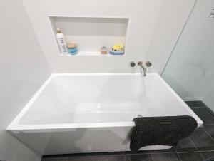 a white bath tub in a bathroom with a sink at Sails in the heart town walk to beach and coffee in Kingscote +36 photos