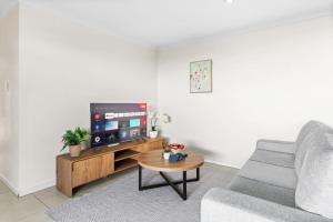 a living room with a couch and a tv at Cozy 2BR Home Quiet Bellbird Park Stay in Bellbird Park