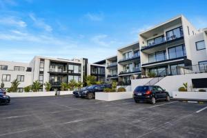 a row of apartment buildings with cars parked in a parking lot at Premium Coastal Abode with Parking Near Beach in Okura