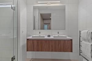 a bathroom with two sinks and a mirror at Premium Coastal Abode with Parking Near Beach in Okura +28 photos
