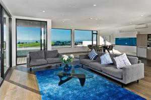 a living room with two couches and a blue rug at Premium Coastal Abode with Parking Near Beach in Okura