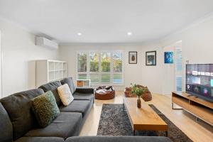 a living room with a couch and a tv at Tranquil 4BR Home Near Parks Shops and Nature Trails in Cornubia Park