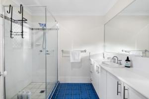 a white bathroom with a shower and a sink at Tranquil 4BR Home Near Parks Shops and Nature Trails in Cornubia Park +30 photos