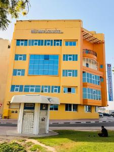 ein gelbes Gebäude, vor dem ein Mann sitzt in der Unterkunft Gulf inn Plaza Hotel LLC in Dubai