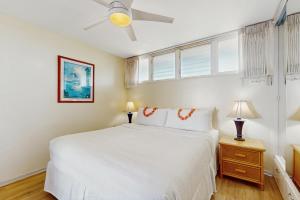 a white bedroom with a bed and a ceiling fan at Hale Ono Loa 406 in Honokowai